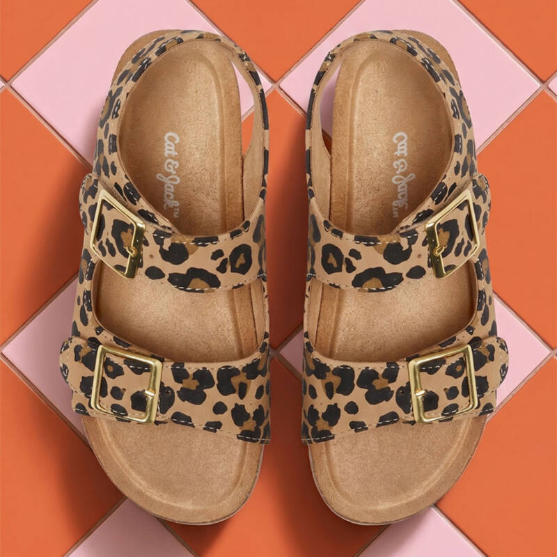 top-down view of leopard print sandals with two gold buckles on tan footbeds.