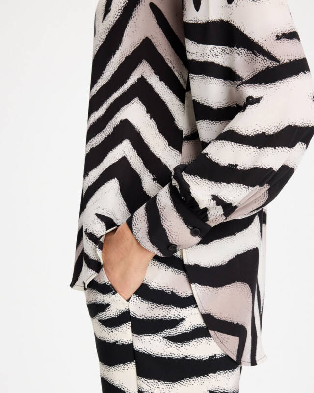 close-up of a long-sleeve blazer with bold black-and-white zebra stripes, hand tucked into the pocket.