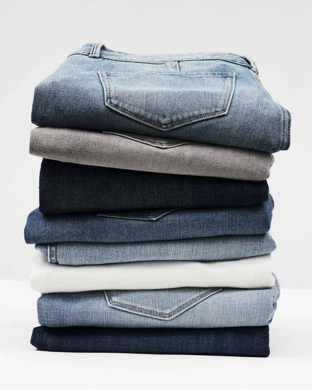 stack of folded denim jeans in light to dark blue shades stacked on a white surface.